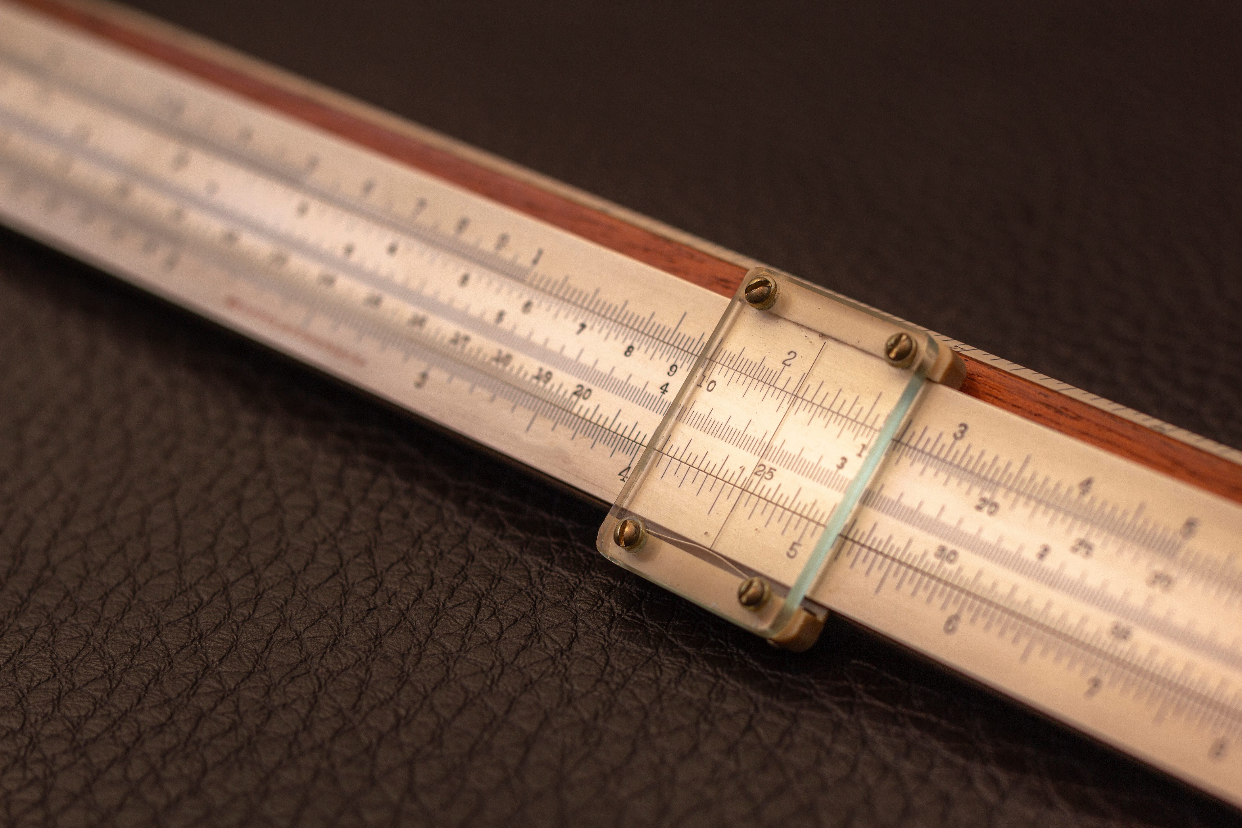 Close up of slide rule from 1915, on a dark background.