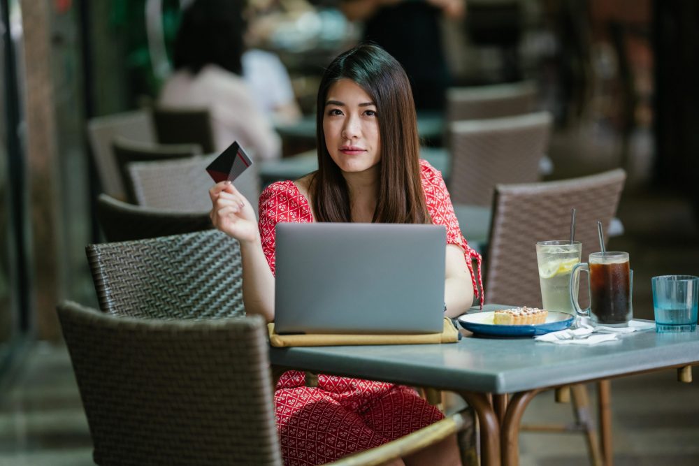 Woman in cafe with laptop and credit card.