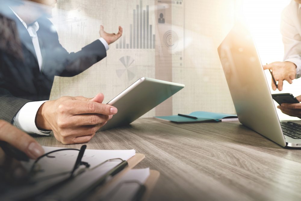 Man holding iPad pointing to bar charts in a meeting