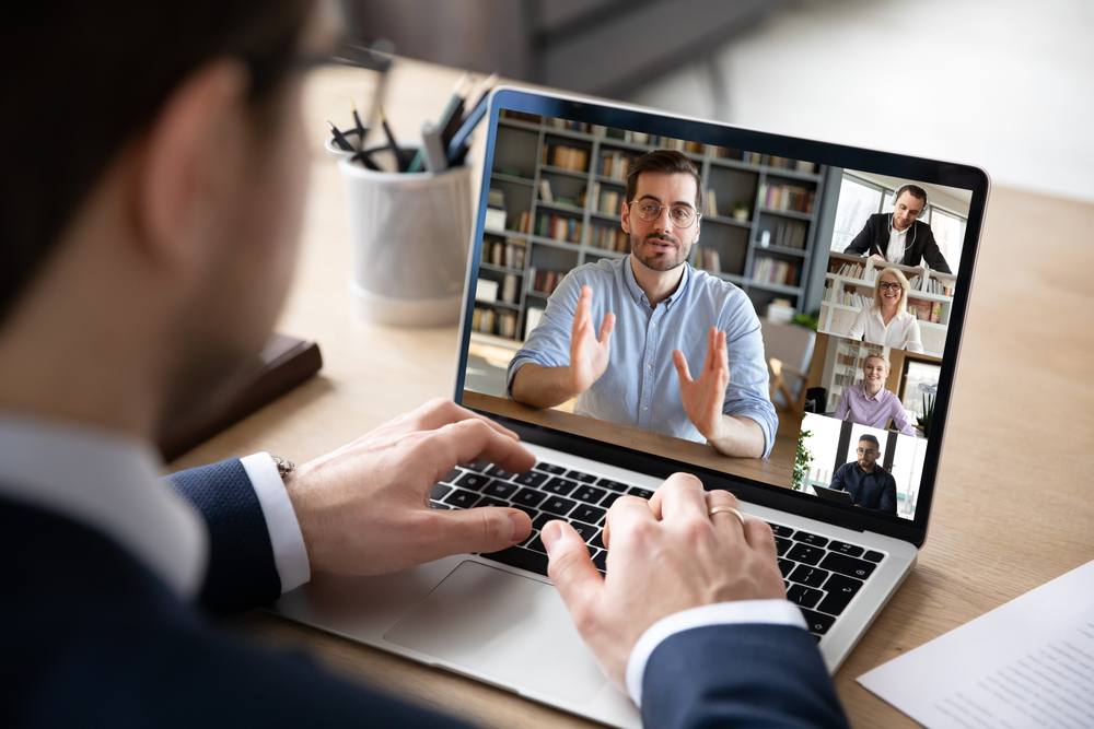 Man joining virtual meeting with other people on his laptop screen.