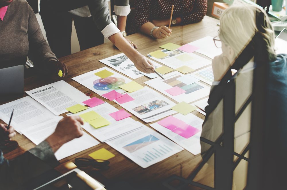 Group of people looking at various documents laid out on a table.