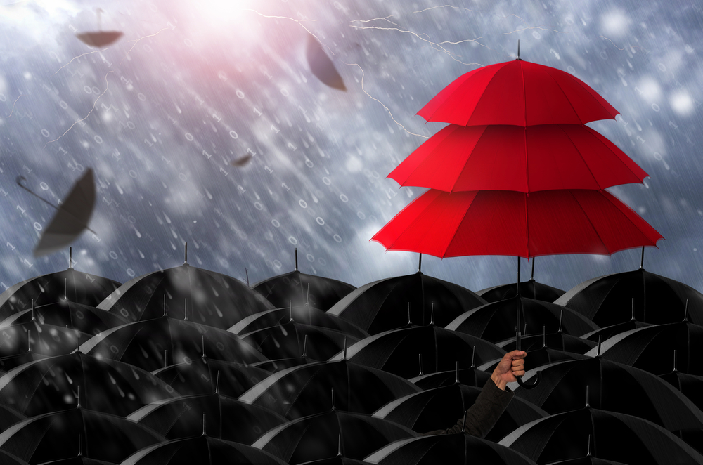 Stack of red umbrellas being held above loads of black umbrellas in the rain.