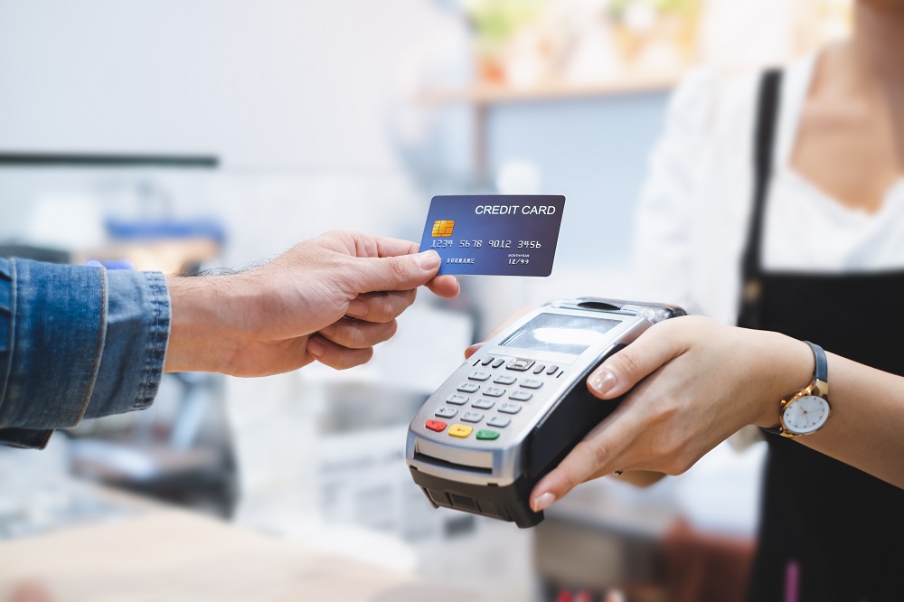 Many using contactless credit card to pay by machine which is being held by a woman.