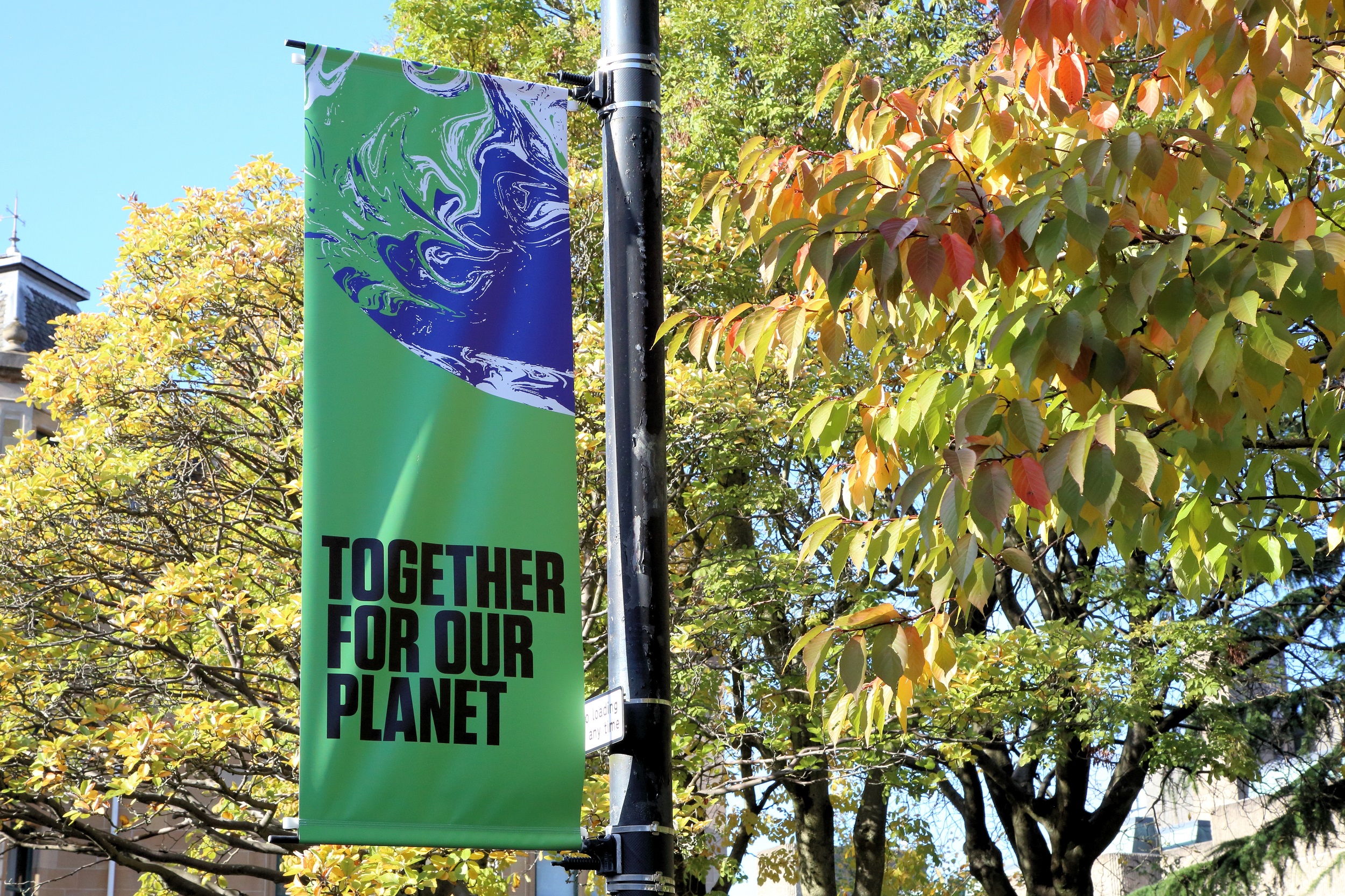 Баннер COP26 с надписью «Вместе для нашей планеты» на уличном фонаре.