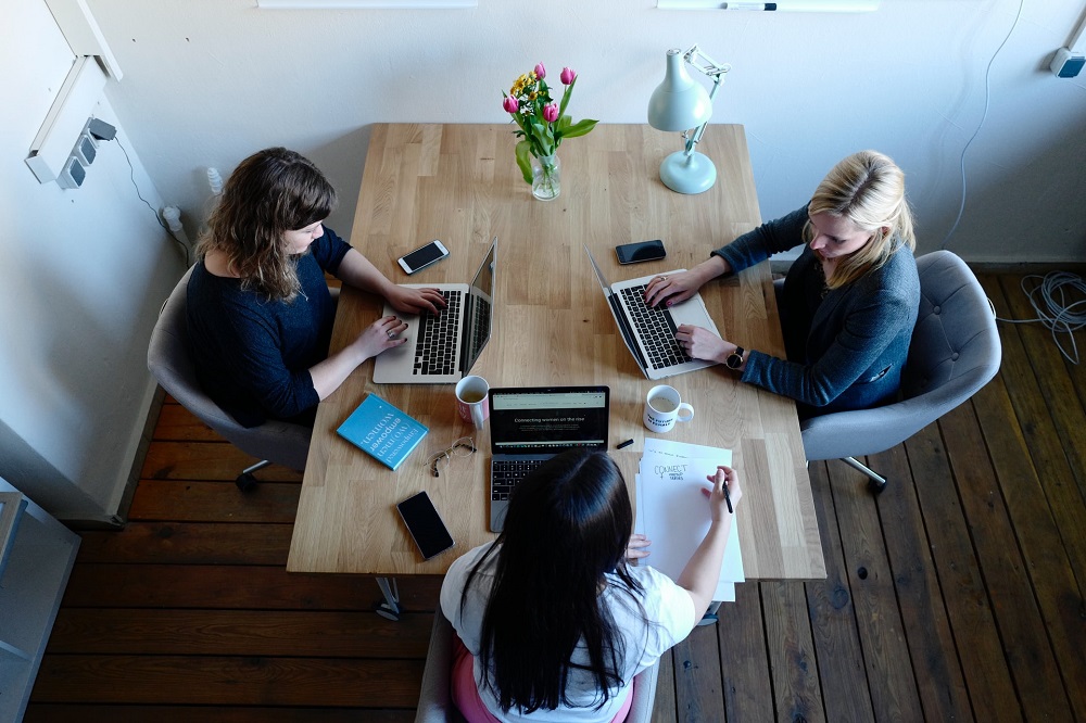 Aerial view of 3 women having a meeting, each one is looking at their laptop.