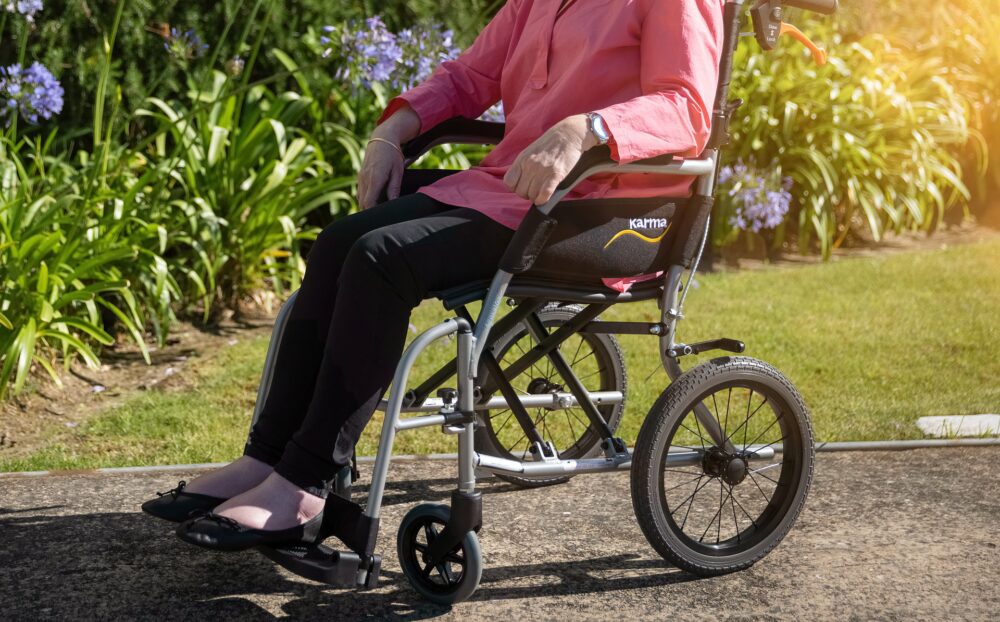 Elderly lady in a wheelchair in a garden.