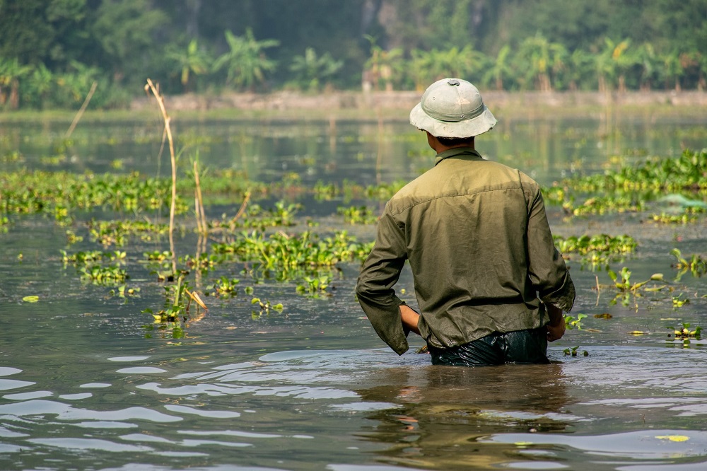 Man stands in flood water. His clothes are soaking wet.