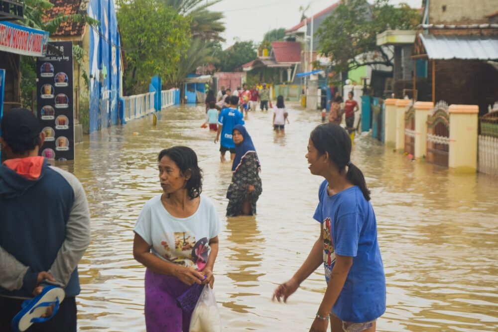 People standing in brown floodwater in the middle of the village.