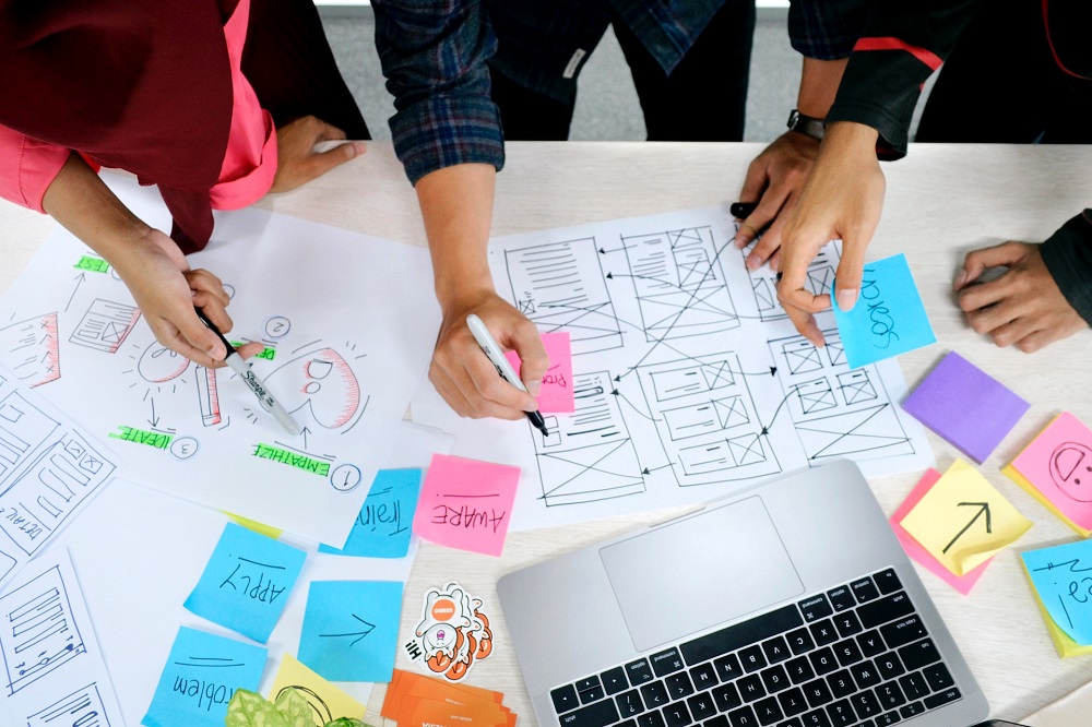 Overhead view of 3 people working on a presentation on a table.