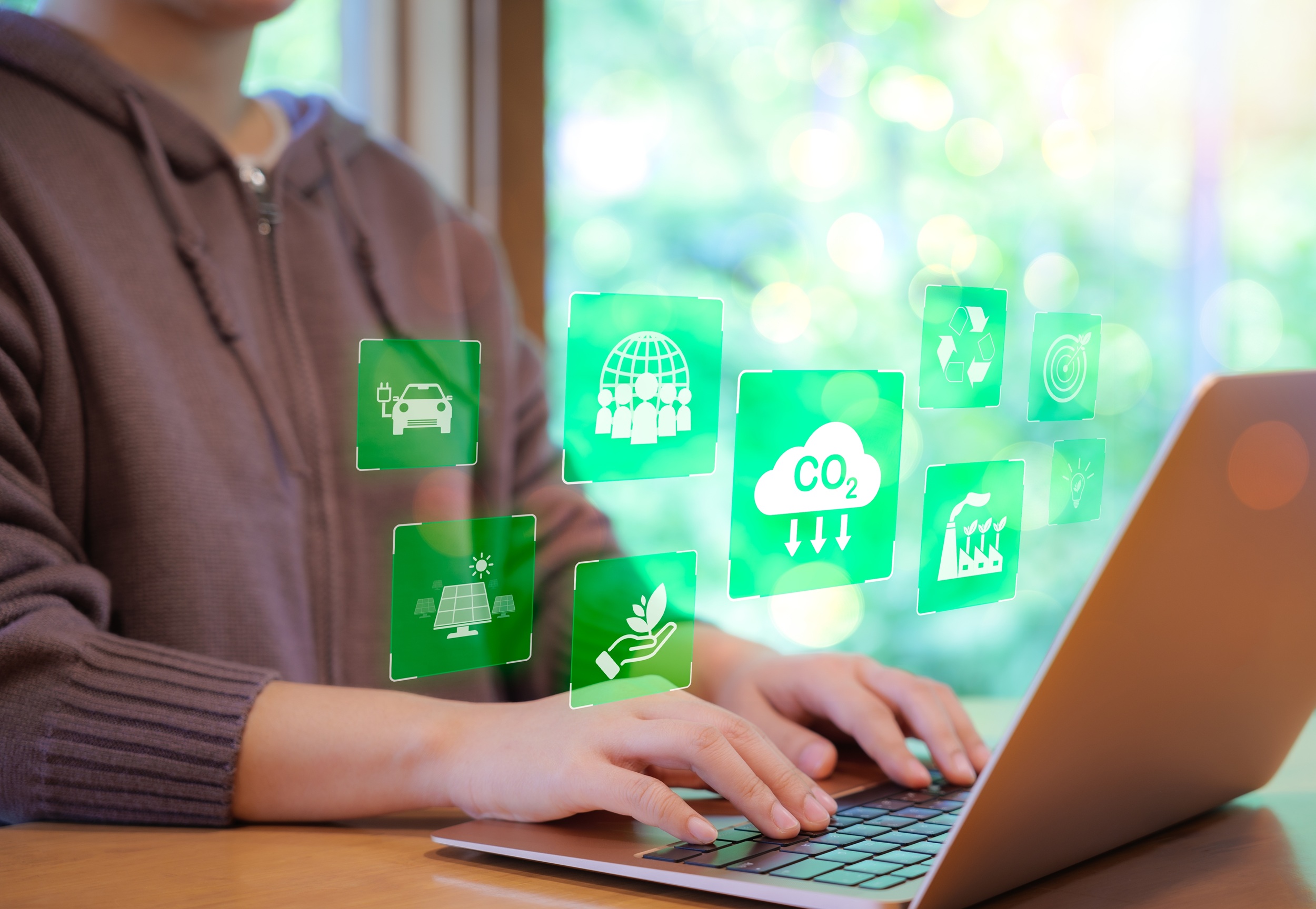 Woman types on laptop keyboard and various environmental images float above the laptop. Credit: Shutterstock
