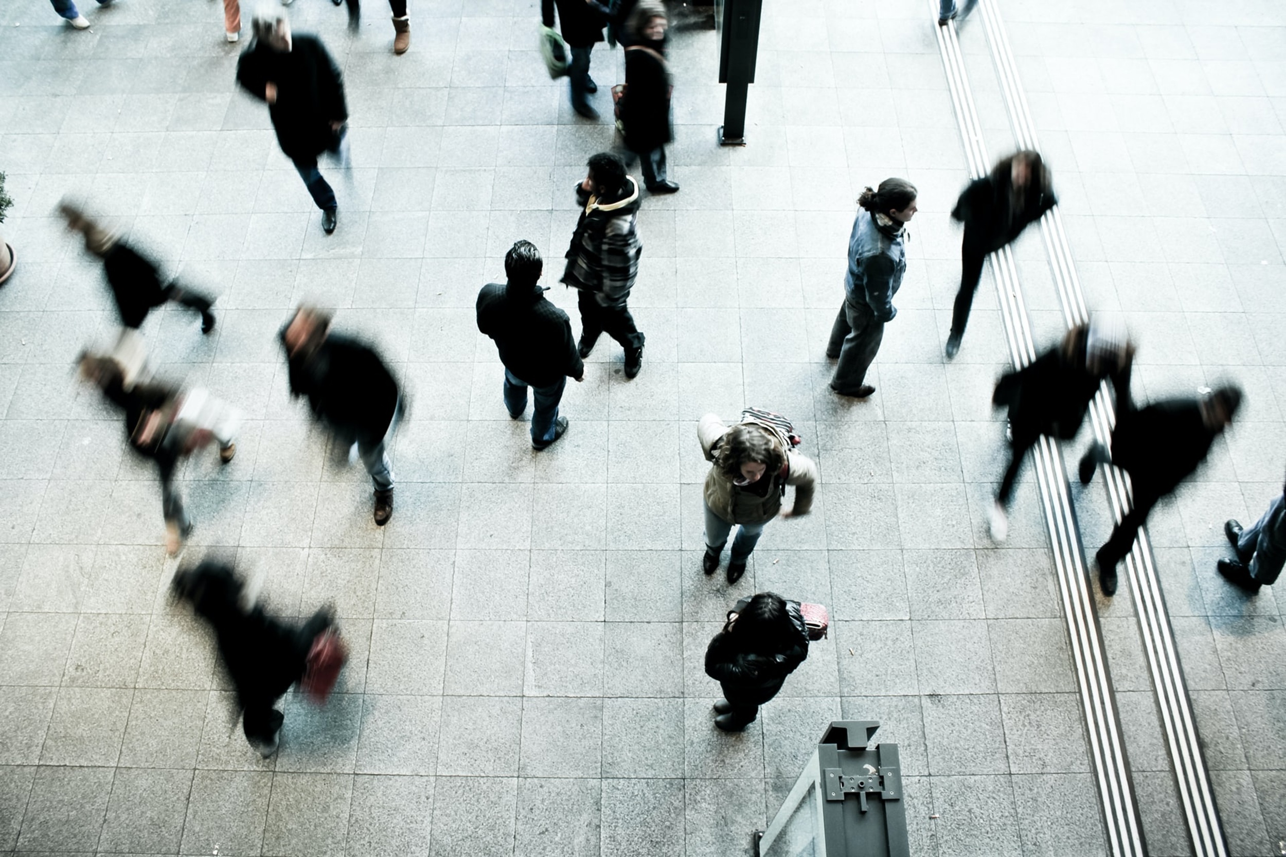 Blurred group of people wearing dark clithes on a ight coloured floor. Credit Unsplash