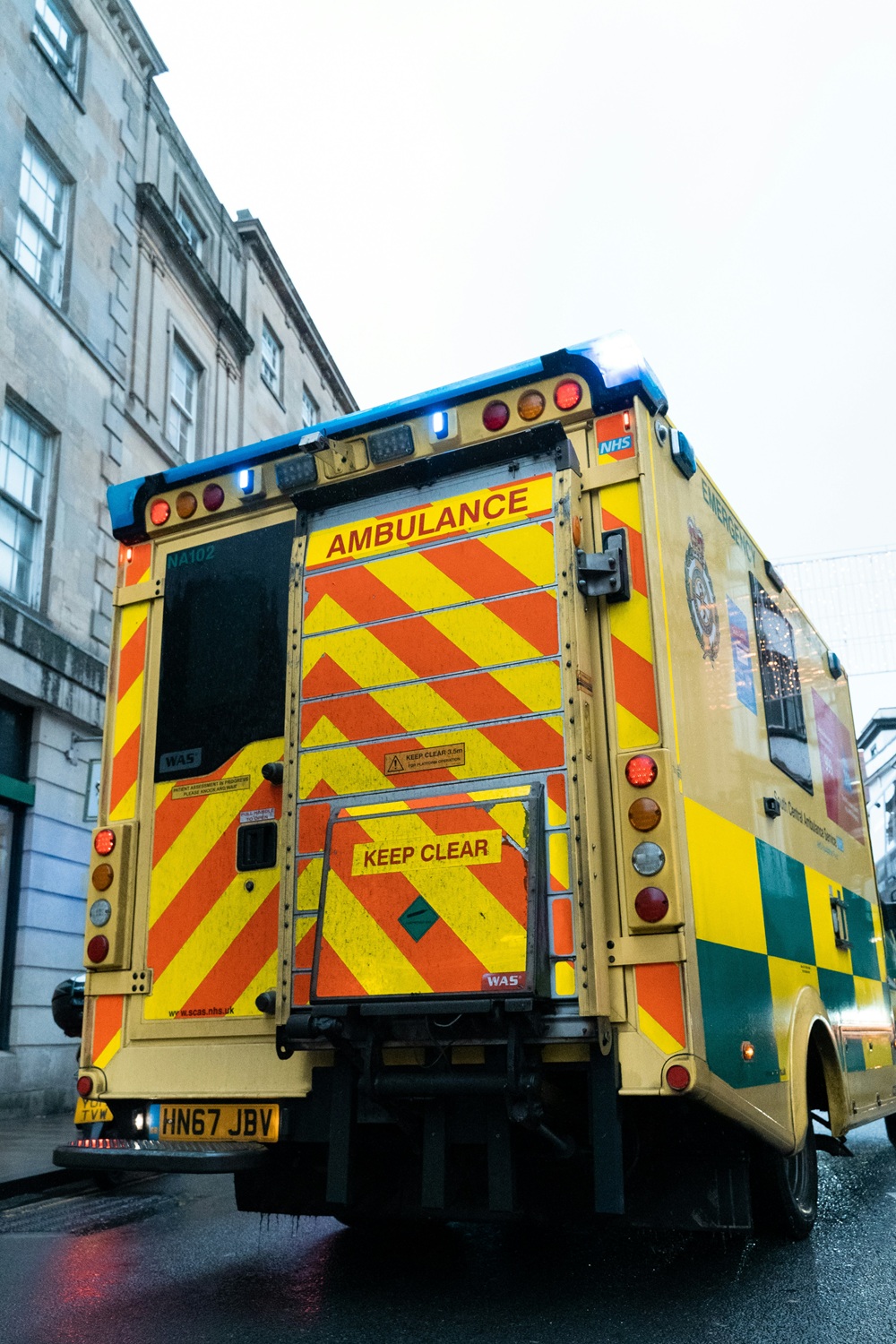 Rear view of an ambulance seen parked next to a building. Credit: Unsplash.