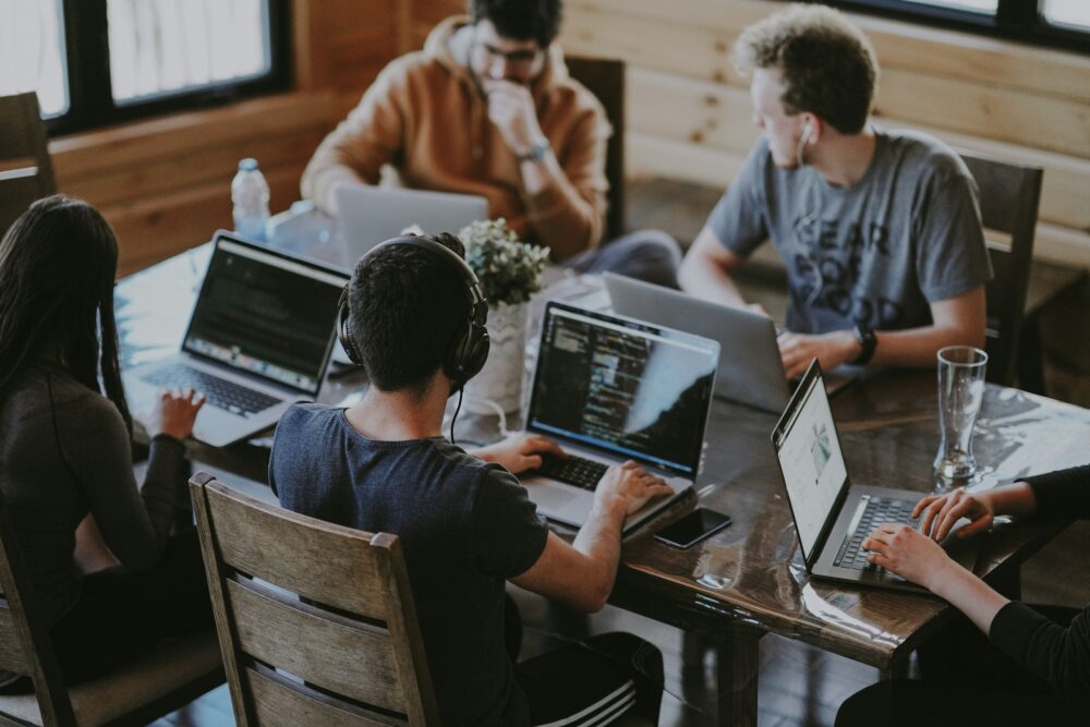 Four people at a table all with laptops. Credit: Annie Spratt, Unsplash.